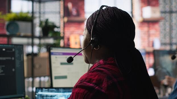 A support specialist wearing a headset while coordinating service by computer.