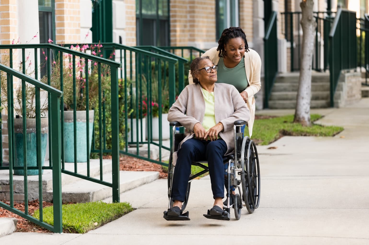 A caregiver helping a senior in a wheelchair outdoors.